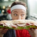 fitness tucna zena drzi sendvic